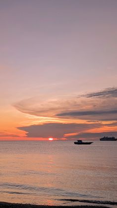 two boats are out on the water at sunset