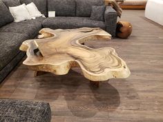 a wooden table sitting on top of a hard wood floor next to a gray couch