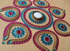 an assortment of beaded items sitting on a wooden table next to a candle holder