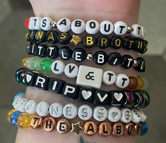 four bracelets with words written on them in different colors and shapes, all stacked together