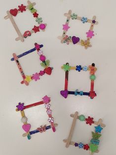 four pieces of clothes pegs are arranged in the shape of frames with flowers and hearts on them