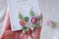 a pair of earrings with crocheted flowers and pearls