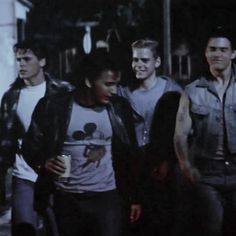 a group of young men standing next to each other on a street corner at night