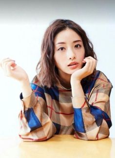 a young woman sitting at a table with her hand on her chin and looking off to the side