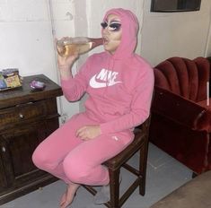 a person in a pink outfit drinking from a wine glass while sitting on a chair