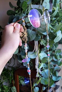 a person holding a pair of glasses in front of a green wreath with leaves and beads