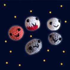 four crocheted balls with faces and stars in the night sky, all made to look like they are smiling