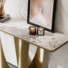 a marble table with two candles on it next to a framed photograph and a gold candle holder