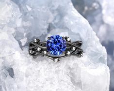 a ring with a blue stone surrounded by white diamonds on top of some ice crystals