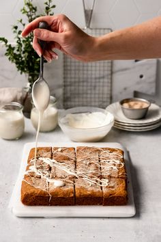 someone is spreading icing on top of some bread with butter and milk in the background