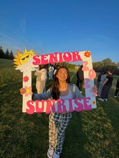 a woman holding up a sign that reads senior sunrise