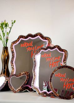 three decorative mirrors sitting on top of a white shelf next to a vase with flowers