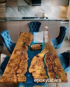 the table is made out of wood and has blue velvet chairs around it, along with marble countertops