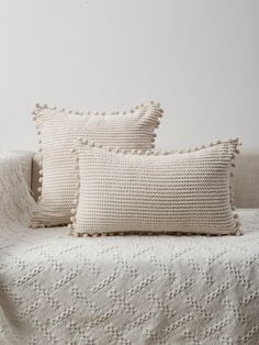 two white pillows sitting on top of a bed