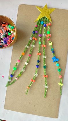 a christmas tree made out of beads and other items on a piece of paper next to a bowl of candy