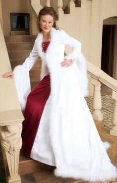 a woman in a white fur coat and red dress standing on stairs with her arms behind her back