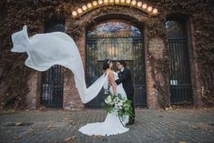 a bride and groom standing in front of an old building with ivy on the doors