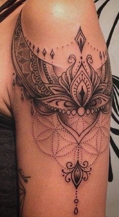 a woman's shoulder with an intricate tattoo design on the back of her arm