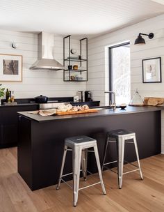 two stools are in front of the kitchen island with an island countertop and black cabinets