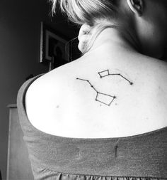 a woman with a tattoo on her upper back shoulder and the zodiac sign sagith