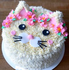 a cake decorated with white frosting and pink flowers on top of a wooden table