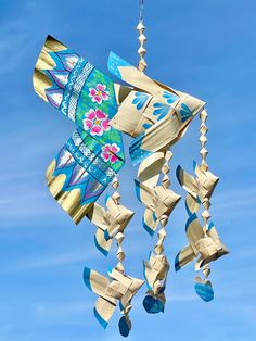 a kite flying in the sky with flowers on it's tail and strings attached to it