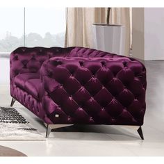 a purple couch sitting on top of a white floor next to a rug and window