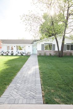 a white house sitting on top of a lush green field next to a sidewalk in front of it