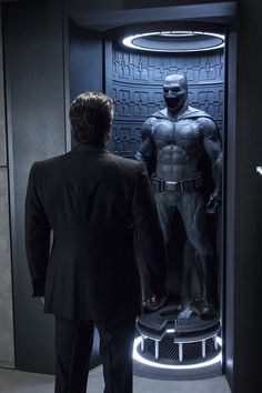 a man standing in front of a display case with a batman figure on it's side