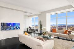 a living room filled with furniture and large windows overlooking the cityscape in the distance