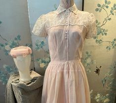 1950 vintage, pink organza dress with white embroidered leaves and flowers. The top has a high neck with a collar with 3 sets of white buttons, also in threes, down the front to the waist. The yoke over the shoulders, including the short sleeves, are embroidered.the hem of the full, gathered skirt is embroidered. The pink linen, circle hat is covered with pink netting decorated with pink leaves. The taffeta lining is strapless on the top. Bust 32", waist 26", bodice length 16", skirt length 33". Feminine Pink Vintage Dress For Wedding, Feminine Pink Vintage Wedding Dress, 1950s Pink Vintage Wedding Dress, Pink Organza Dress, Circle Hat, Feminine Clothing, Embroidered Leaves, 1950 Vintage, Organza Dress