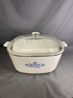 a casserole dish with a glass lid and blue flowers on the side,