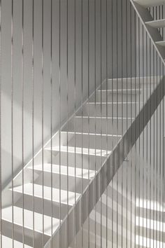 an empty staircase with white walls and metal bars on the railings, in front of a window