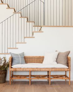 a white couch with pillows on it in front of a stair case