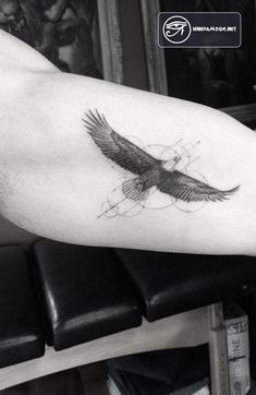 a black and white photo of a bird tattoo on the right arm, with an eagle flying above it