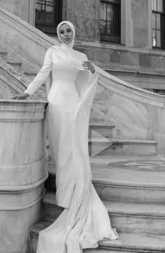 a woman in a white dress standing on some steps