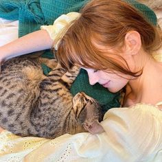 a woman laying in bed with her cat