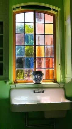 a white sink sitting under a window next to a green wall