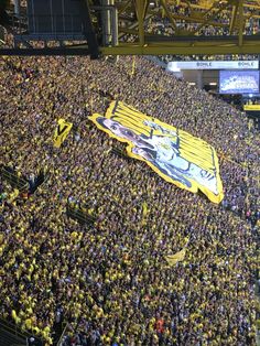 a large group of people in a stadium with one person holding up a yellow flag