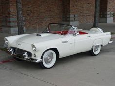 an old white convertible car parked in front of a brick building