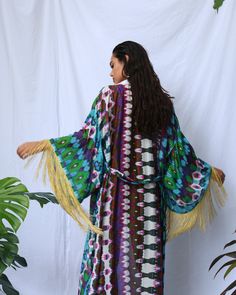 Elaborado en seda multicolor, destaca con flecos dorados que adornan las mangas y la cintura. Tiene la opción de atar el cinturón detrás o dejarlo abierto en la espalda, según tu preferencia. Multicolor Kimono Sleeves Robe For Festival, Multicolor Wrap Kimono For Festivals, Long Sleeve Festival Kimono With Fringe, Festival Long Sleeve Kimono With Fringe, Long Sleeve Fringe Kimono For Festivals, Traditional Long Kimono With Tassels, Long Sleeve Kimono With Tassels For Festival, Long-sleeved Tassel Kimono For Festivals, Long Sleeve Tassel Kimono For Festivals