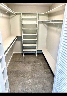 an empty walk in closet with white shelving