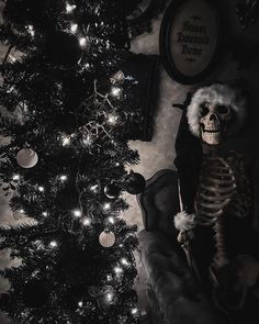 a skeleton sitting next to a christmas tree