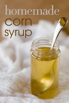 a jar filled with corn syrup on top of a white towel next to a spoon