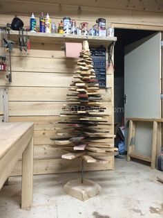 a christmas tree made out of wooden planks in a workshop with tools on the shelves