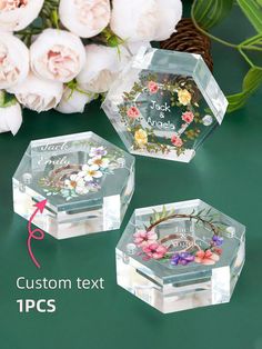 three clear acrylic boxes with floral designs on them and flowers in the background