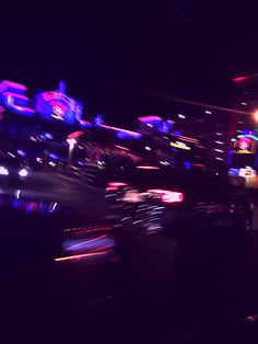 blurry photograph of cars at night with neon signs on the roof and lights in the background