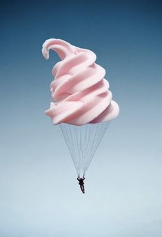 a person parasailing in the sky with pink ice cream