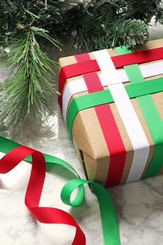 a wrapped present sitting on top of a table next to a green and red ribbon