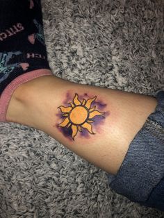 a woman's arm with a small sun tattoo on it